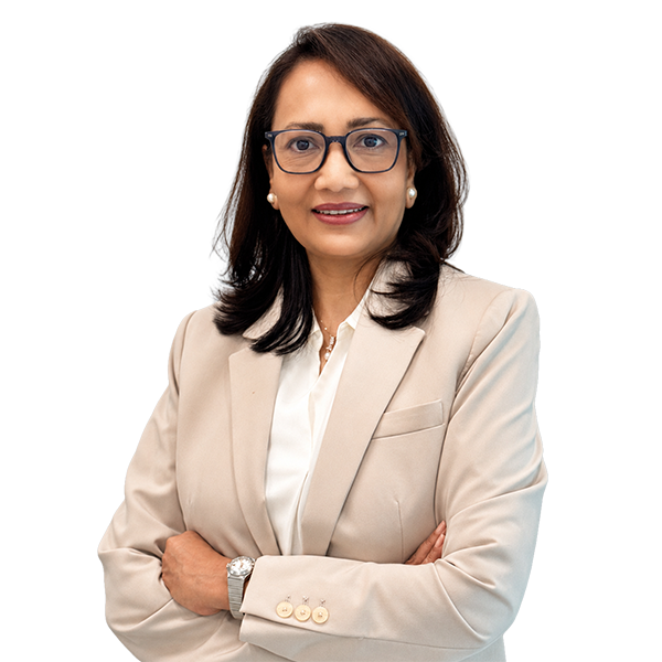 Professional woman in a beige blazer with glasses, arms crossed, smiling at the camera.